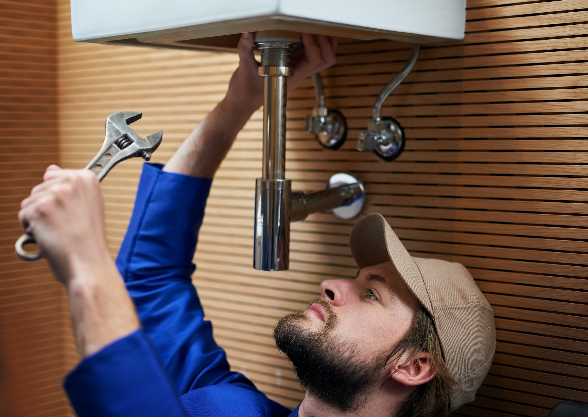 Hes your number one plumber. Shot of a plumber repairing a pipe underneath a sink.